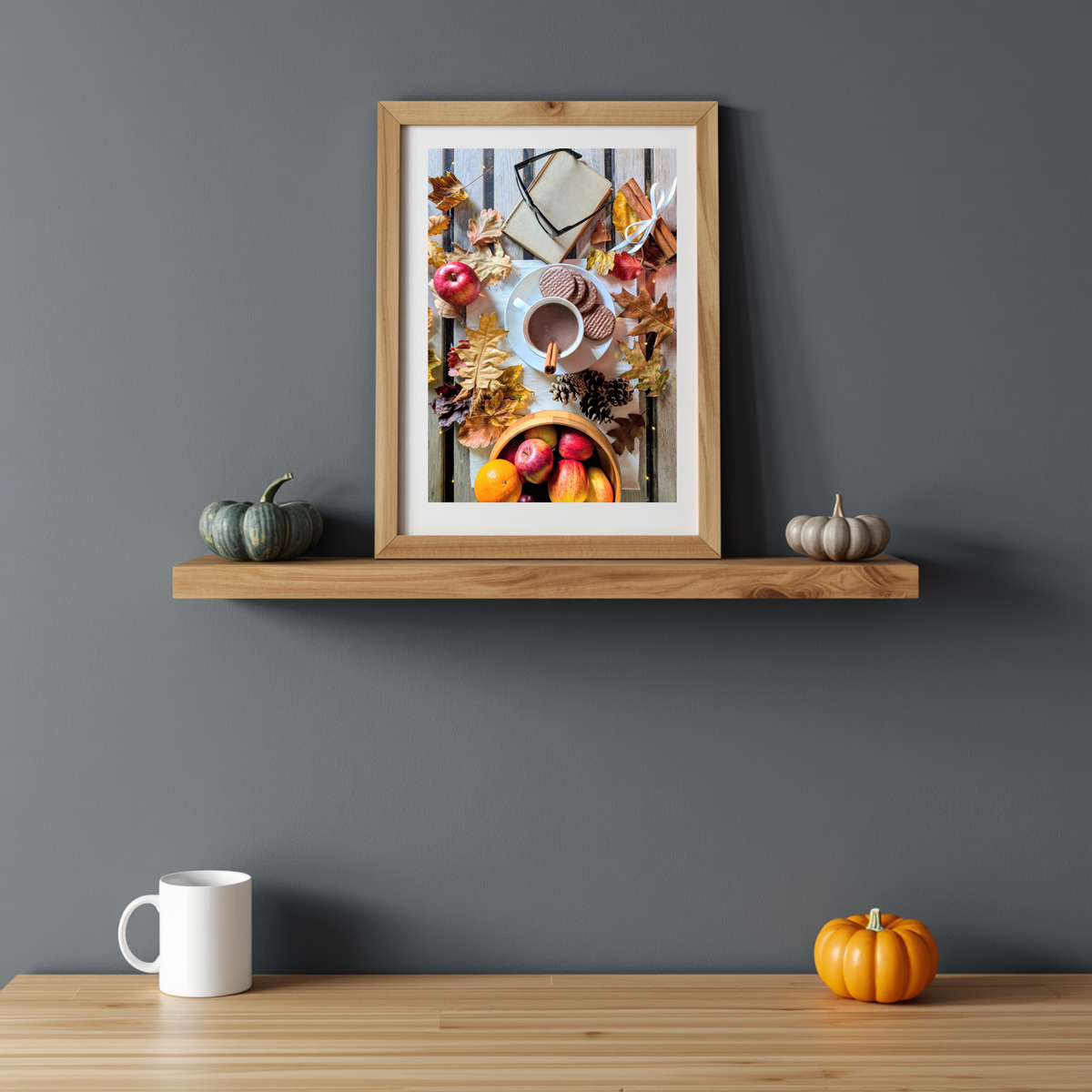 Framed autumn artwork showing cocoa cup, apples, leaves, and a small cinnamon stick