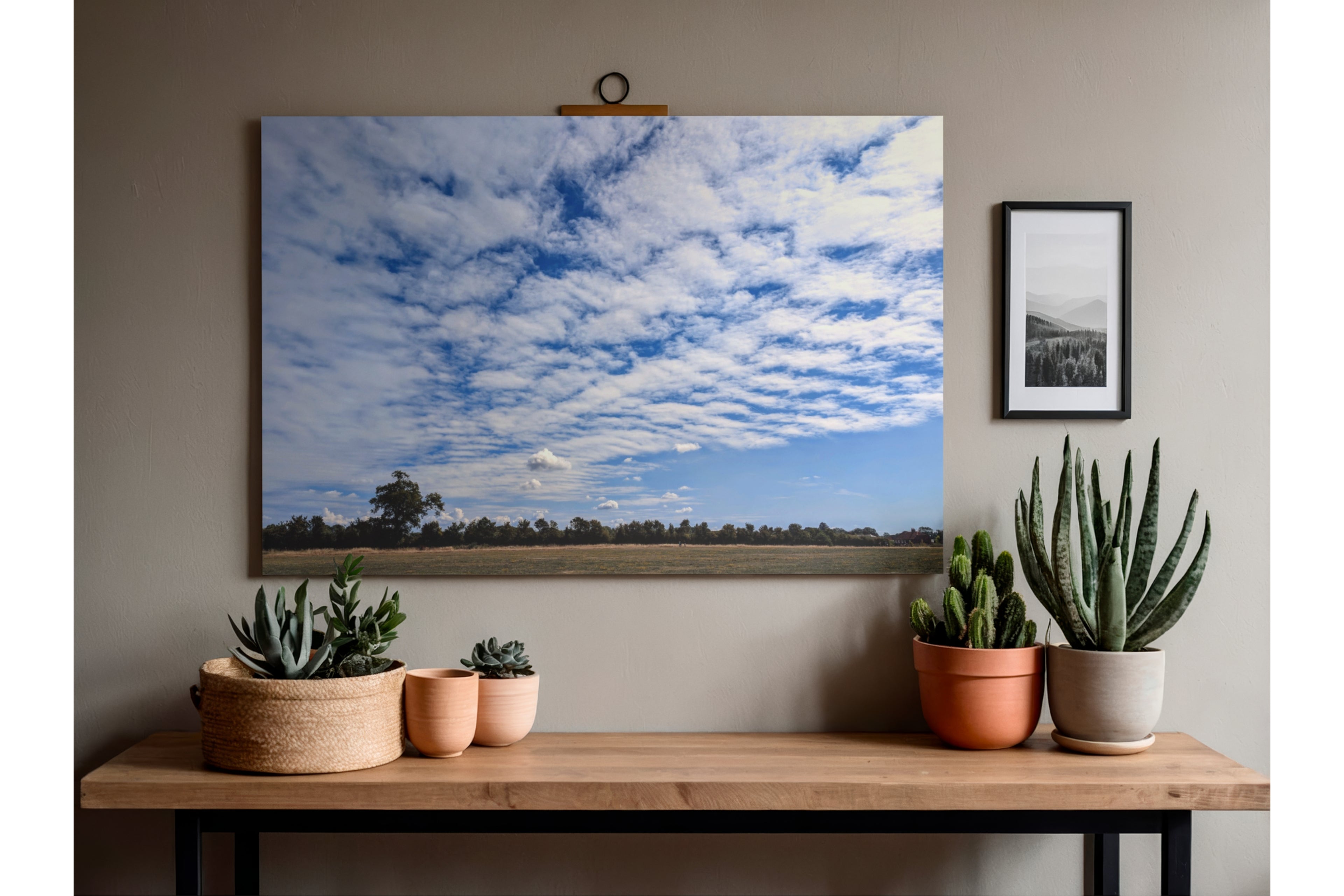 Framed landscape cloud formation artwork: blue textured clouds over fields and trees