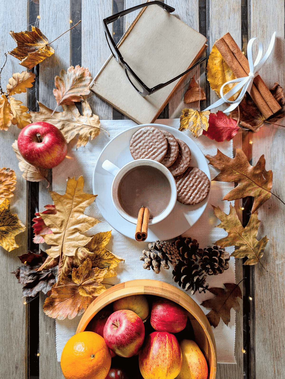 Autumn-themed framed artwork featuring cocoa cup, fruit, dry leaves, and woven coasters